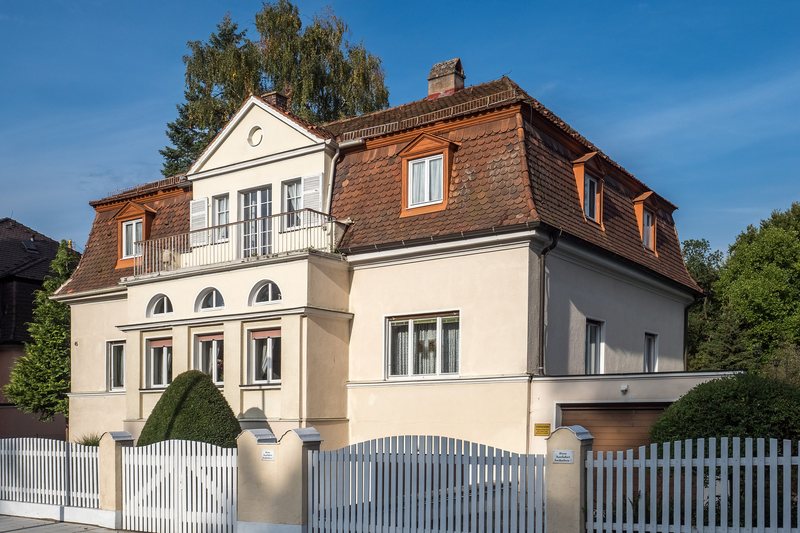 Einfamilienhaus mit Garten, weißer Zaun, Bäume und blauer Himmel