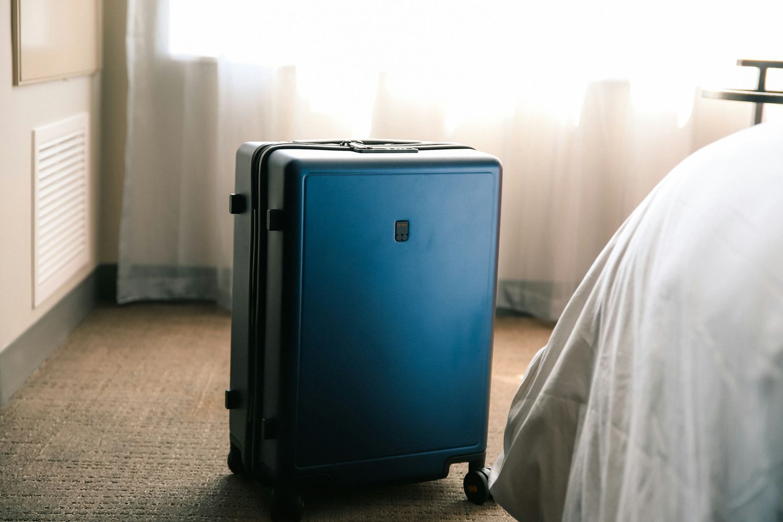 Ein Koffer neben dem Bett in einem hellen Zimmer