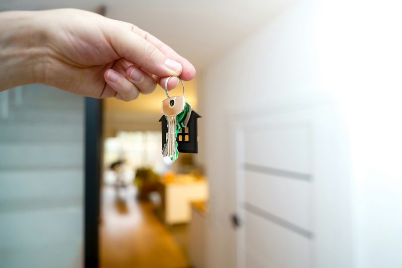 Eine Hand hält einen Wohnungsschlüssel vor einer hellen Wohnung